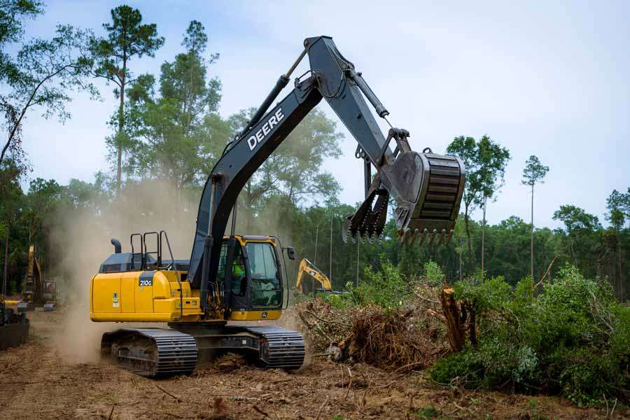 Excavator clearing trees and brush from a wooded parcel in Florida